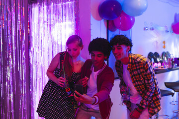 Teen diverse friends taking selfie at lively birthday party with colorful balloons, at home