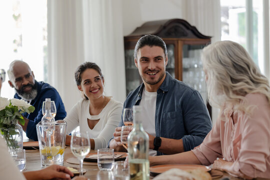 Friends enjoying conversation and drinks at elegant small casual wedding reception table, at home