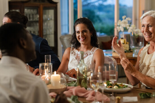Guests enjoying dinner, smiling and clapping at elegant wedding reception