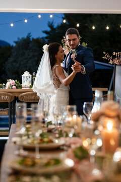 Bride and groom dancing joyfully under string lights at outdoor wedding reception