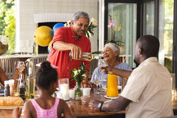 Pouring wine, grandfather at diverse family gathering, everyone having good time, in garden
