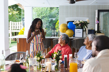 Speaking to diverse family at in garden celebration, woman sharing joyful moment