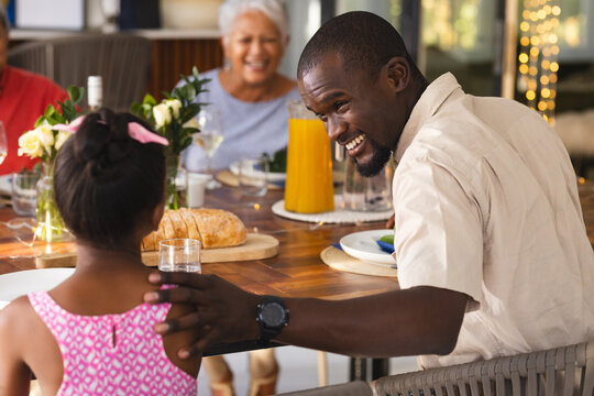 Father and daughter bonding, smiling over diverse family meal, in garden