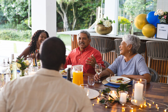Diverse family enjoying in garden meal, sharing stories and laughter at festive gathering