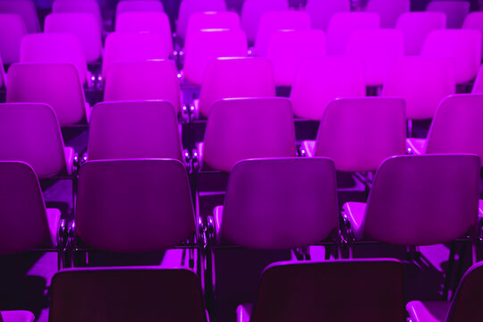 Rows of purple lit empty chairs at a conference of AI in Amsterdam