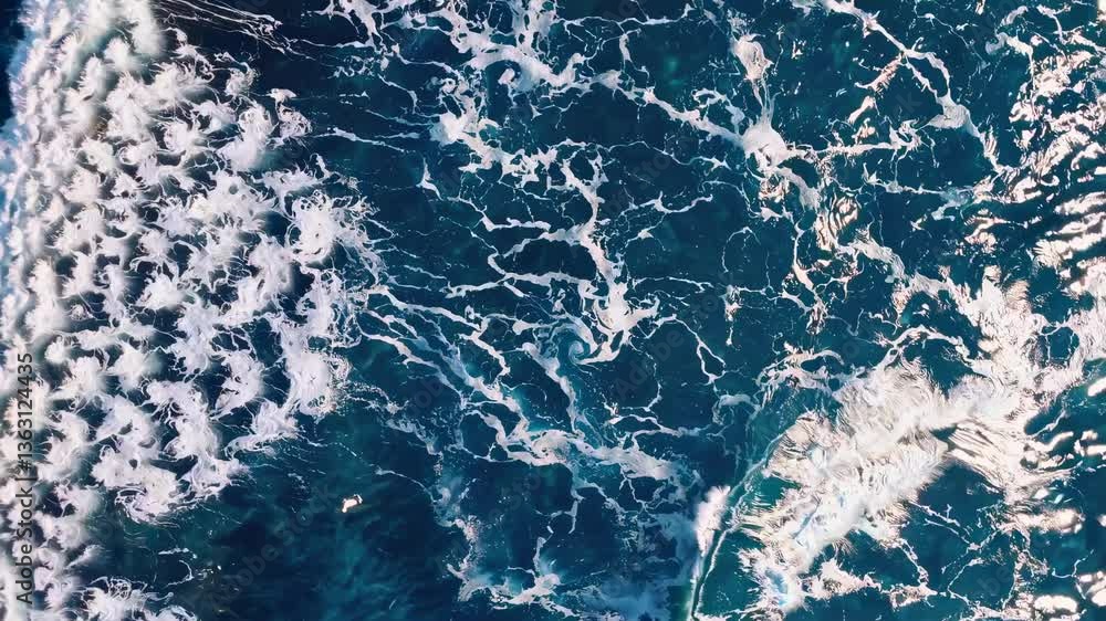 Poster aerial view of ocean waves crashing, creating intricate patterns. the video captures the dynamic, na