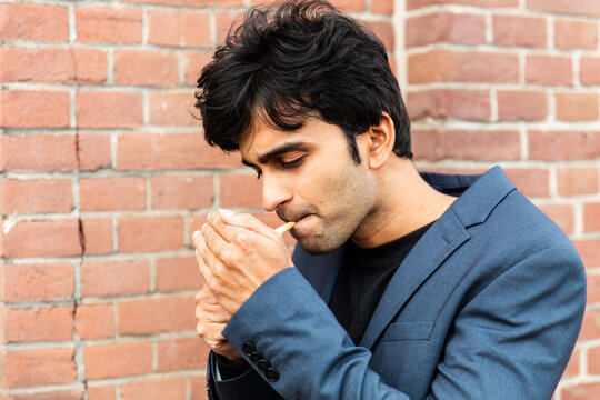 Indian Man Lighting Cigarette Against Brick Wall at a conference of AI