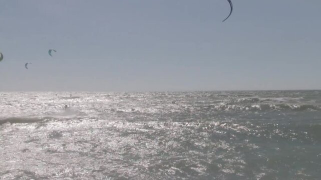 Kitesurfers glide over the waves enjoying on a windy day at the Canos de Meca, a wild, scenic beach along Vejer de la Frontera's coast in Cadiz, Andalusia, Spain.