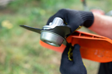 Trimming grass in the backyard with a detailed look at the trimmer blades. Person inspects the...