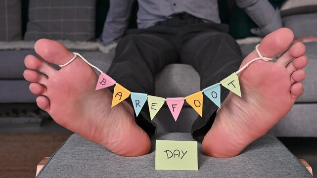 Close-up of Man's Bare Feet Swaying and Wiggling Toes with "Bare Foot Day" Decoration