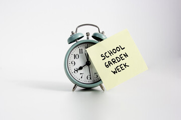 Alarm Clock with School Garden Reminder. alarm clock with a sticky note reading "School Garden Week," symbolizing time management and educational gardening events. Garden week concept