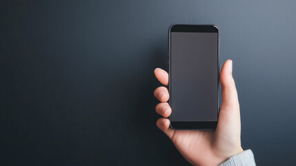 A hand holds a black smartphone against a muted gray background revealing modern digital simplicity
