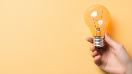 A hand holds a yellow lightbulb against a pale yellow background. Simple, bright, and conveys a concept of ideas and