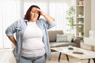 Stressed and worried plus size woman holding her head at home