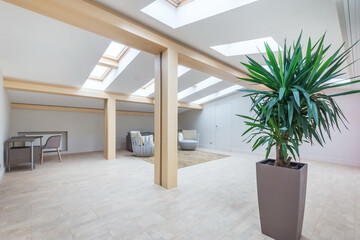 Magnificent design of the attic of a private house. Ceiling beams made of light wood, windows in the roof. Furnished.