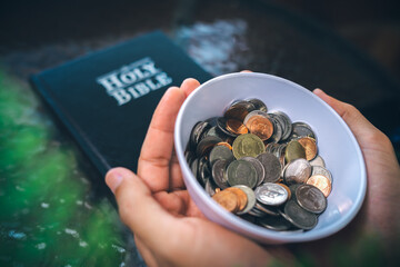 Coins with Holy Bible, a closeup, Christian biblical concept of tithing, Biblical concept of Christian offering