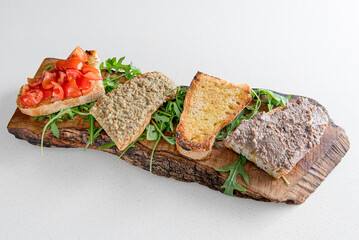 plate of bruschetta served on a rustic wooden chopping board, with fresh tomatoes, cream of mushroom, olive oil, with spreadable cream, meat.