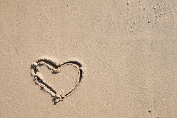 Heart drawn in sand on empty tropical beach during sunset. Vacation and Travel Concept. Valentines Day or Wedding concept.