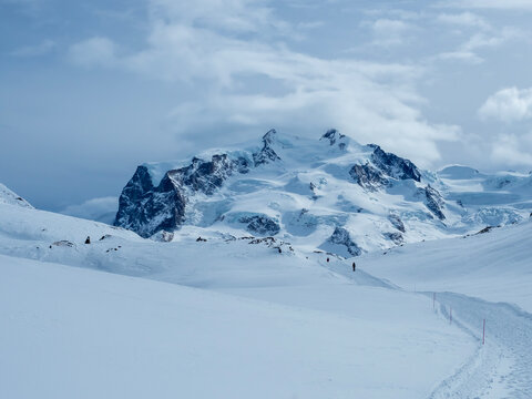 Monte Rosa mountain range in winter with deep snow and cloudy sky.