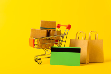 Online shopping concept.Cardboard box and shopping bags in a trolley on a bright colored...