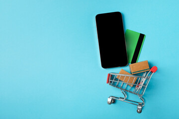 Online shopping concept.Cardboard box and shopping bags in a trolley on a bright colored...