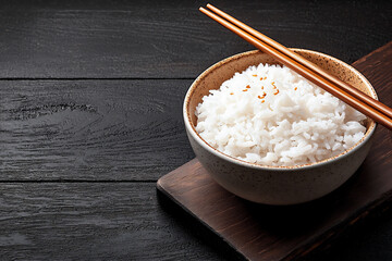 artistic shot of a bowl of rice with chopsticks resting on the rim,