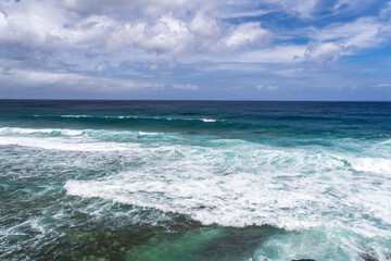 Turquoise ocean waves breaking on tropical shoreline. Coastal view of crystal clear ocean waves with white foam.Pristine seascape