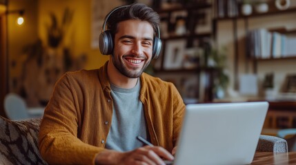 Obraz premium A cheerful young man enjoys his time at a warm, inviting cafe, using a laptop to work creatively. He listens to music through headphones, exuding positivity and focus as sunlight streams in