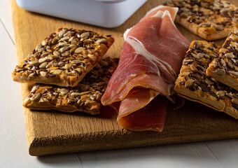 Prosciutto and grain cracker on a cutting board