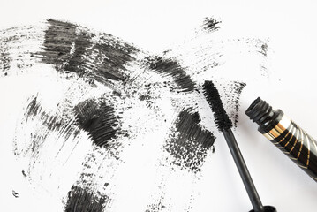 Smear of black mascara and applicator isolated on white, top view.