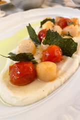 Fried Portuguese scallops in white wine sauce with lemon, tomatoes and toast. Seafood.