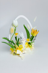 Easter bouquet with a white bunny, tulips, and daffodils in a basket