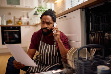 Worried African American man contacting customers support regarding broken dishwasher.