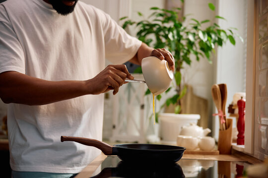 Close up of black man preparing scrambled eggs in kitchen. - Powered by Adobe