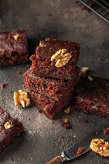 Stack of delicious brownie pieces with hazelnuts on dark background