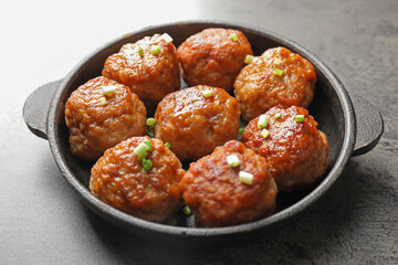 Tasty meatballs with green onion in baking dish on grey table, closeup