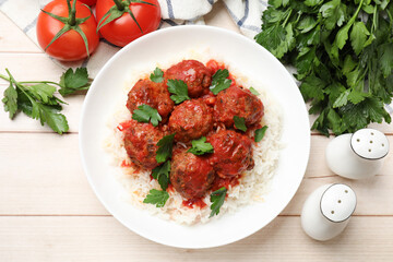 Delicious meatballs with rice, sauce and parsley on light wooden table, flat lay