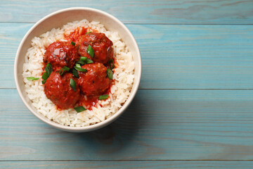 Tasty meatballs with sauce and rice on light blue wooden table, top view. Space for text
