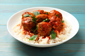 Tasty meatballs with sauce and rice on light blue wooden table, closeup