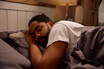Fototapeta premium African American man sleeping in his bed at night.