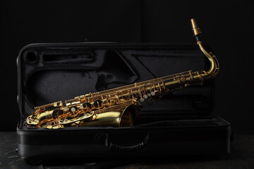Fototapeta premium Jazz. Golden saxophone in case on black textured table