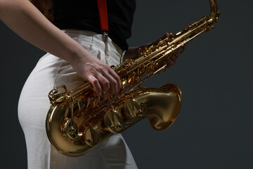 Professional musician with saxophone on grey background, closeup