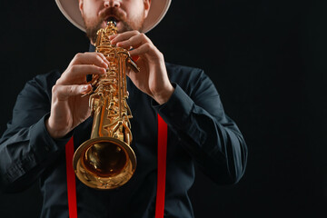 Fototapeta premium Professional musician playing soprano saxophone on black background, closeup