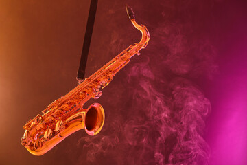 Naklejka premium Golden saxophone on color background with smoke. Space for text