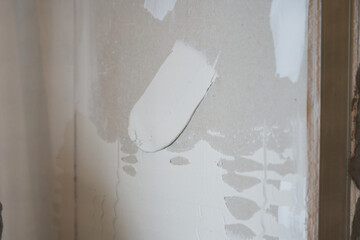 The rough texture of the white plaster. A patch of putty. The textured background of the putty is...
