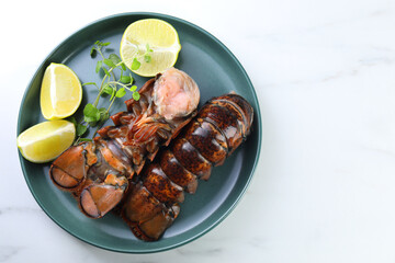 Raw lobster tails, lime and microgreens on white marble table, top view. Space for text