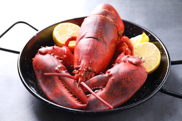 Delicious boiled lobster with lemon pieces on grey table, closeup