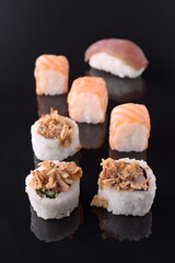 Variety of delicious sushi rolls and nigiri reflecting on black background