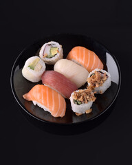 Variety of delicious nigiri and maki sushi displayed on a black plate