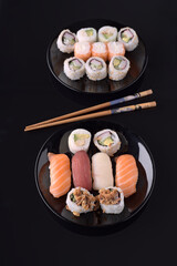 Delicious sushi assortment displayed on black plates with chopsticks